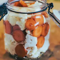 Ein Glas mit Karottenscheiben und Blumenkohl, bereit zum Blumenkohl fermentieren.