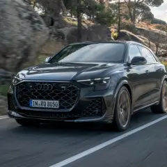 Czarny Audi RS Q8 pędzi po krętej drodze wśród skał i drzew. Sprawdź aktualną audi rsq8 cena!