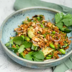 En skål med en fräsch sallad med ris, edamamebönor, gurka, jordnötter och koriander. Den krispiga riset ger en härlig textur.