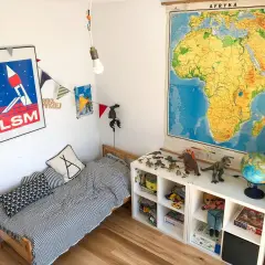 Pokój dziecka po metamorfozie: łóżko w paski, dinozaury i mapa Afryki.