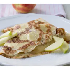 Zwei goldbraune Pfannkuchen mit Apfelmus gefüllt, garniert mit Apfelspalten und Puderzucker.