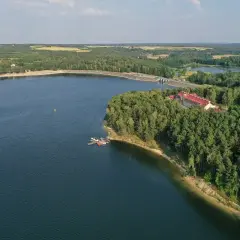 Zalew Chańcza otoczony lasem, z hotelem i pomostem.
