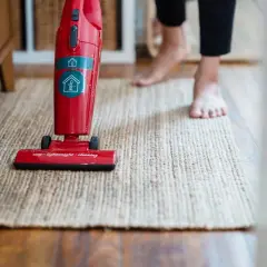Czerwony odkurzacz Electrolux na dywanie. Gdzie jest bezpiecznik? Może w uchwycie, gdzie są przyciski?