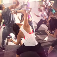 Un gruppo di persone balla con energia durante una lezione di Zumba. Movimento e divertimento per chi vuole che zumba fa dimagrire.