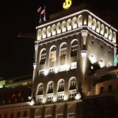 Nocą oświetlony budynek BGŻ z charakterystycznym logo. Widać łukowe okna i flagi na dachu.