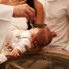 Cérémonie de baptême : l'eau bénite coule sur la tête du bébé. Une douce chanson de baptême accompagne ce moment sacré.