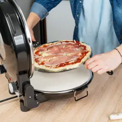 Osoba wkłada pizzę z szynką do pieca. Szybko i łatwo przygotujesz idealne danie.