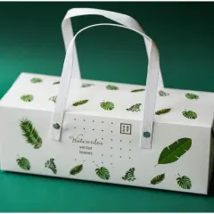Eleganckie pudełko z motywem liści, idealne, by dowiedzieć się, jak zapakować wino na ślub. Białe, z uchwytem, gotowe na wyjątkową okazję.