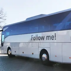 Autokar z napisem "Follow me!" czeka na pasażerów przy lotnisku w Koszalinie.