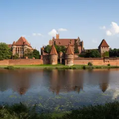 Potężny zamek z czerwonej cegły, największy zamek na świecie, odbija się w spokojnej wodzie.