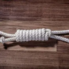 Zbliżenie na węzeł łączący dwie białe liny na drewnianym tle.