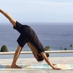 Hombre en postura de perro boca abajo, practicando yoga flow que es una secuencia fluida de posturas.
