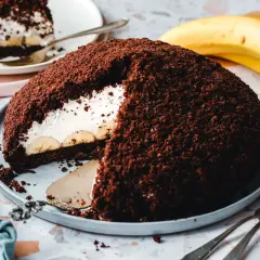Ein saftiger veganer Maulwurfkuchen mit Bananen und Sahne, bedeckt mit Schokoladenkrümeln.