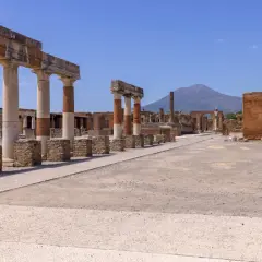 Ruiny Pompejów z kolumnadą i Wezuwiuszem w tle. Warto kupić pompeje bilety online, by uniknąć kolejek.
