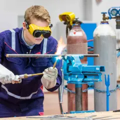 Ein junger Mann schweißt Rohre, eine praktische Übung für Weiterbildungsmöglichkeiten als Anlagenmechaniker SHK.