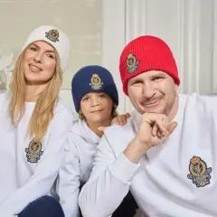 Filip Chajzer z rodziną w czapkach i bluzach z herbem. Uśmiechnięty tata, mama i ich dzieci.