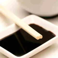 Bacchette appoggiate su una ciotolina di salsa di soia, un condimento che, se consumato in eccesso, può causare diarrea.