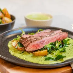 Skivad flankstek med perfekt flankstek temp, serverad med rostade potatisar och en krämig örtsås.