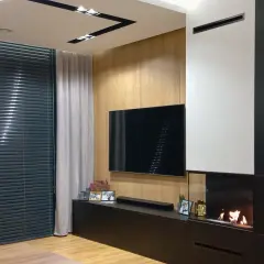 Nowoczesny salon z telewizorem i palącym się kominkiem bio do zabudowy.