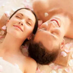 Para spędza relaksujący dzień w spa, leżąc wśród płatków róż.