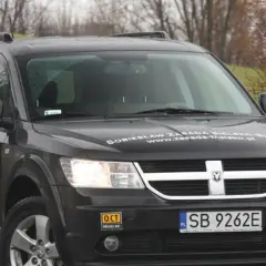 Czarny Dodge Journey z naklejkami "OCT UWOLNIJ MOC" i "Sobiesław Zasada Bielsko-Biała".