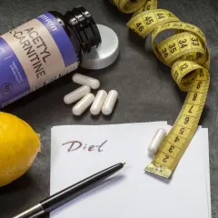Flasche Acetyl-L-Carnitin, Maßband, Zitrone und Notiz "Diet". Die L-Carnitin Wirkung wird hier für eine Diät dargestellt.