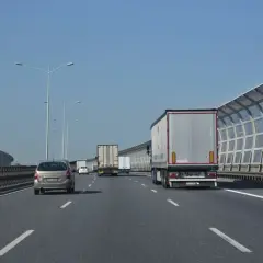 Jadę lewym pasem autostrady za ciężarówką. W oddali widać inne pojazdy i ekrany akustyczne.