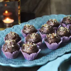 Mini cupcakes choklad med krämig frosting och hackade nötter, serverade på ett vackert fat.
