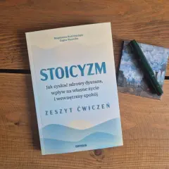 Książki o stoicyzmie na drewnianym stole. Zeszyt ćwiczeń "Stoicyzm" zachęca do zdrowego dystansu i wewnętrznego spokoju.