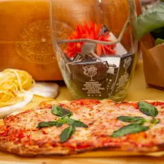 Pyszne rodzaje pizzy, makaron i ser parmezan. W tle szklany wazon z dekoracjami i kwiatami.