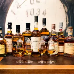 Rząd butelek whisky, w tym Dalwhinnie, Balvenie, Jura, Oban, Glenmorangie, Monkey Shoulder. Idealne na tanie dobre whisky.