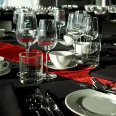 Elegancko nakryty stół na stypę, z kieliszkami do wina i szklankami, sugeruje, że alkohol może być serwowany.