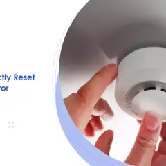 Ein Finger drückt auf einen Rauchmelder, der nicht ausgeht. Anleitung zum Zurücksetzen.