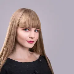 Blondynka z prostą, gęstą grzywką, która zakrywa czoło. Różne rodzaje grzywek mogą podkreślić urodę.