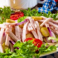 Ein leckerer Wurstsalat mit Tomaten, Gurken und Zwiebeln, perfekt für ein deftiges wurstsalat rezept. Dazu ein Glas Bier.