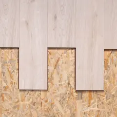 Jasne deski podłogowe na tle płyty wiórowej. Alternatywa dla płyt OSB w budownictwie.