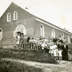Grupa ludzi, w tym dzieci, pozuje przed budynkiem kościoła. Prawdopodobnie to zgromadzenie mormonów z lat 30. XX wieku.