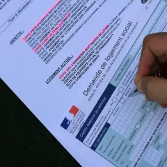 Formulaire de demande de mutation pour un logement social. Un stylo remplit les champs d'une demande de logement social.