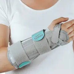 Szara orteza na nadgarstek, która zapewnia stabilizację, lepsza niż gips.