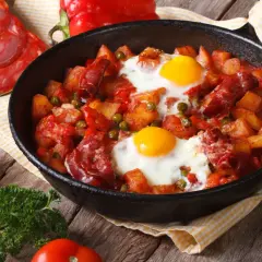 Pyszny obiad z jajek z ziemniakami, chorizo i groszkiem w patelni.