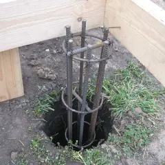Zbrojenie słupa fundamentowego pod starym drewnianym domem. Przygotowanie do wylania betonu.