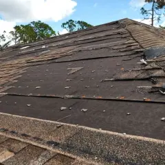 Damaged asphalt shingle roof repair needed. Many shingles are torn, lifted, or missing, exposing the underlayment.