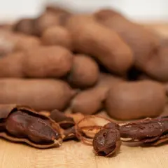 Ein Haufen brauner Tamarindenfrüchte, eine davon geöffnet, zeigt das dunkle Fruchtfleisch. Vielseitige Tamarinde Verwendung in Küche und Medizin.