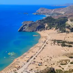 Rodos: turkusowe morze, piaszczysta plaża z leżakami i wodnym parkiem rozrywki, górzyste wybrzeże.