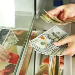 Wymiana dolarów w kantorze bez dowodu. Dłonie przekazują sobie banknoty 100 USD.