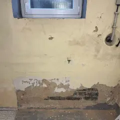 Feuchte Wände im Altbau: Putz bröckelt, Ziegel sind sichtbar. Zeit für eine professionelle Keller trockenlegen Maßnahme.