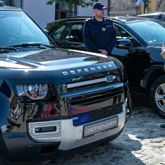 Nowy Land Rover Defender, mały pojazd szynowy, lśni w słońcu. Obok stoją funkcjonariusze w mundurach.