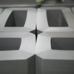 Część rdzenia transformatora, ułożone obok siebie metalowe elementy tworzące kształt litery "E".