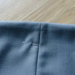Szare spodnie z zaznaczonymi zaszewkami, gotowe do szycia. Szpilki trzymają materiał.