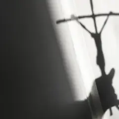 Schatten eines Kreuzes mit Jesusfigur, der eine kritische Auseinandersetzung mit evangelischen Freikirchen andeutet.